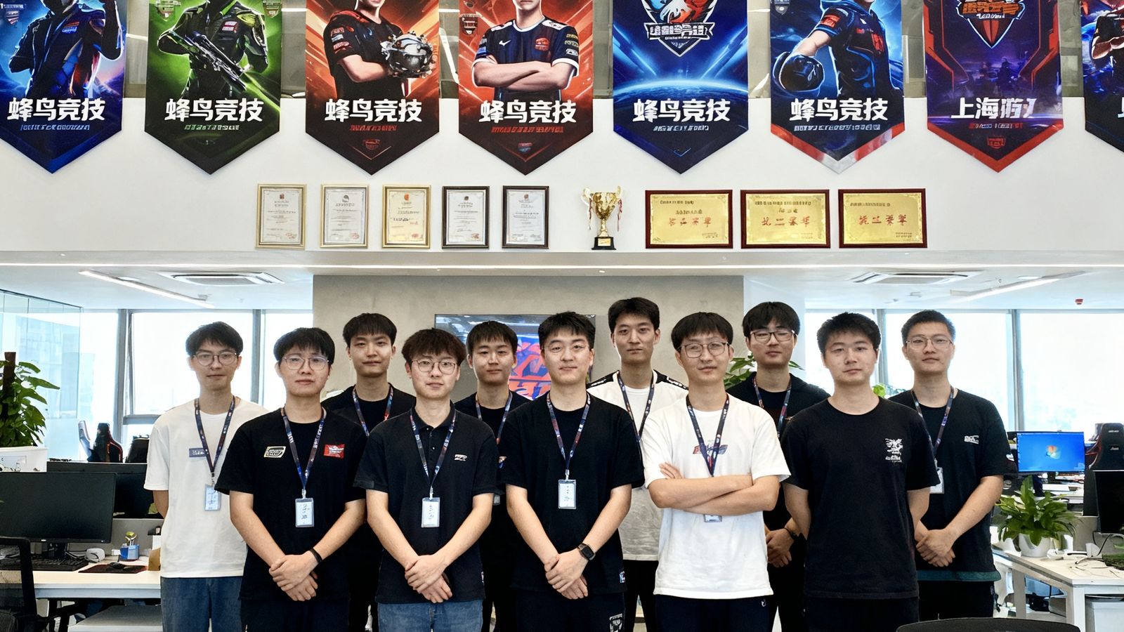 蜂鸟竞技上海总部团队在开放式办公区合影，环境现代明亮，墙面装饰着电竞赛事海报和荣誉证书